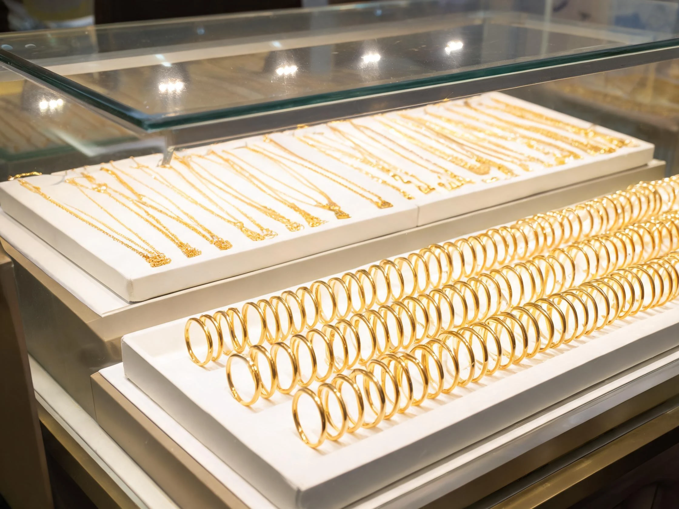 Tiered gold chain trays inside a jewelry display counter with stepped tray wells