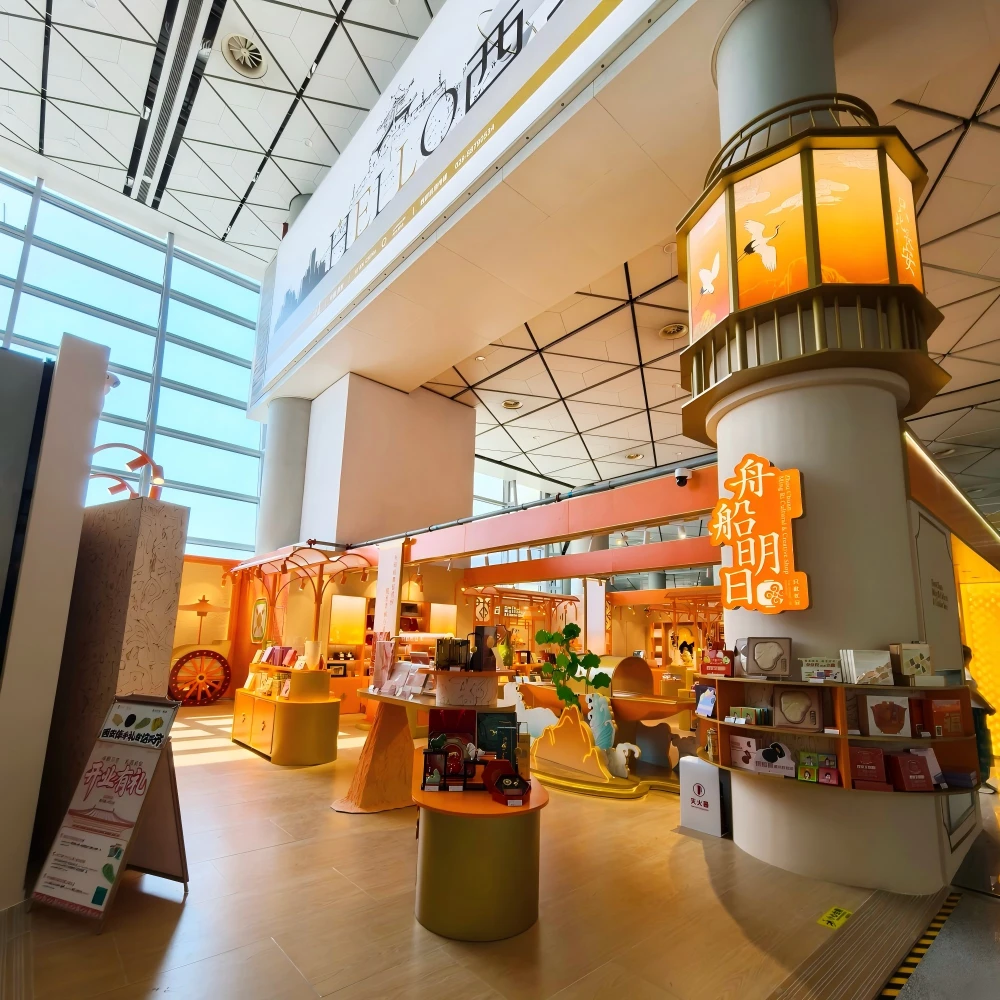Full island view of a cultural-heritage retail shop fit out inside an Asia airport installation with vibrant orange display cabinets and a central illuminated pillar