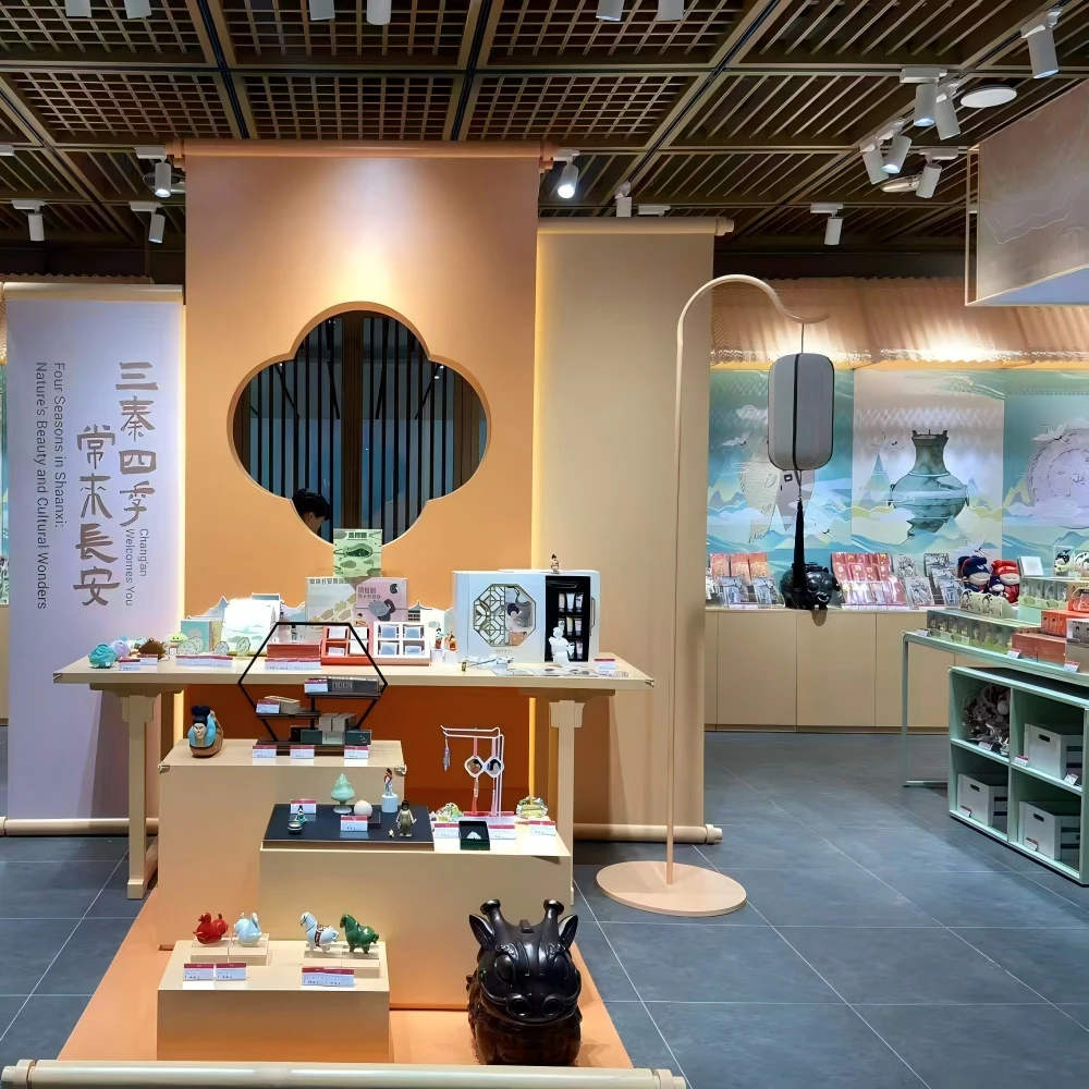 Warm-tone cultural display corner with scroll banners, quatrefoil window frames, and tiered merchandising tables in a retail interior design installation