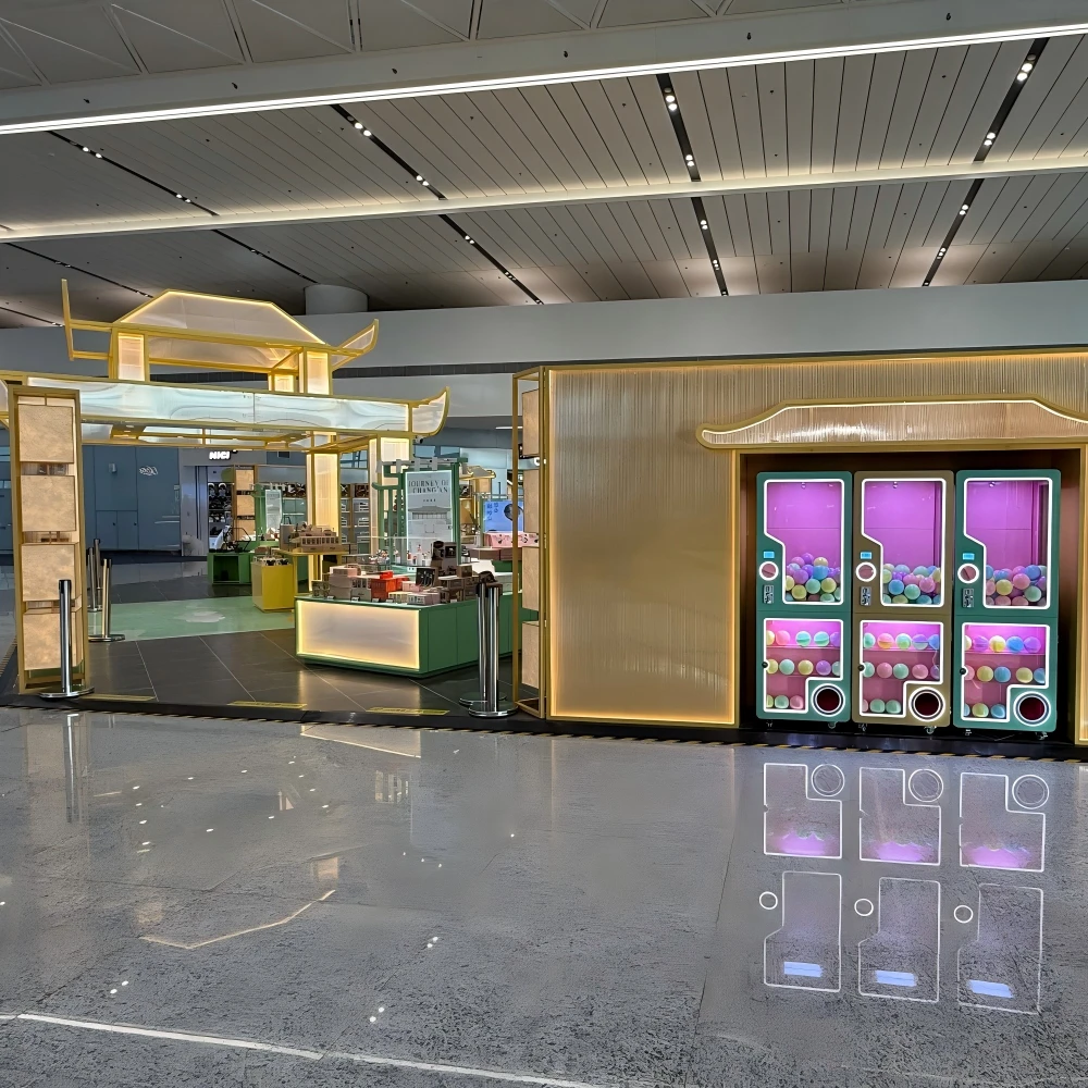 Interactive capsule-toy station integrated into a golden pavilion frame with backlit acrylic panels in a modern retail store design live store