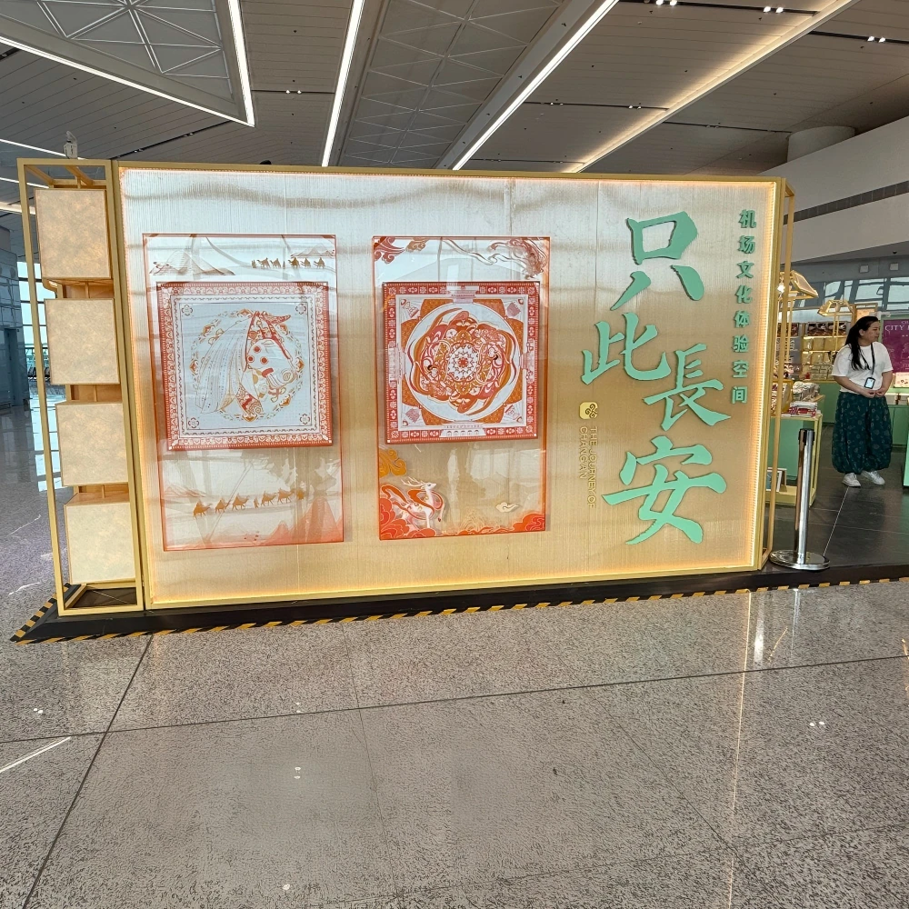 Branded experience wall with silk-scarf display frames and illuminated cultural graphics in a retail interior design installation