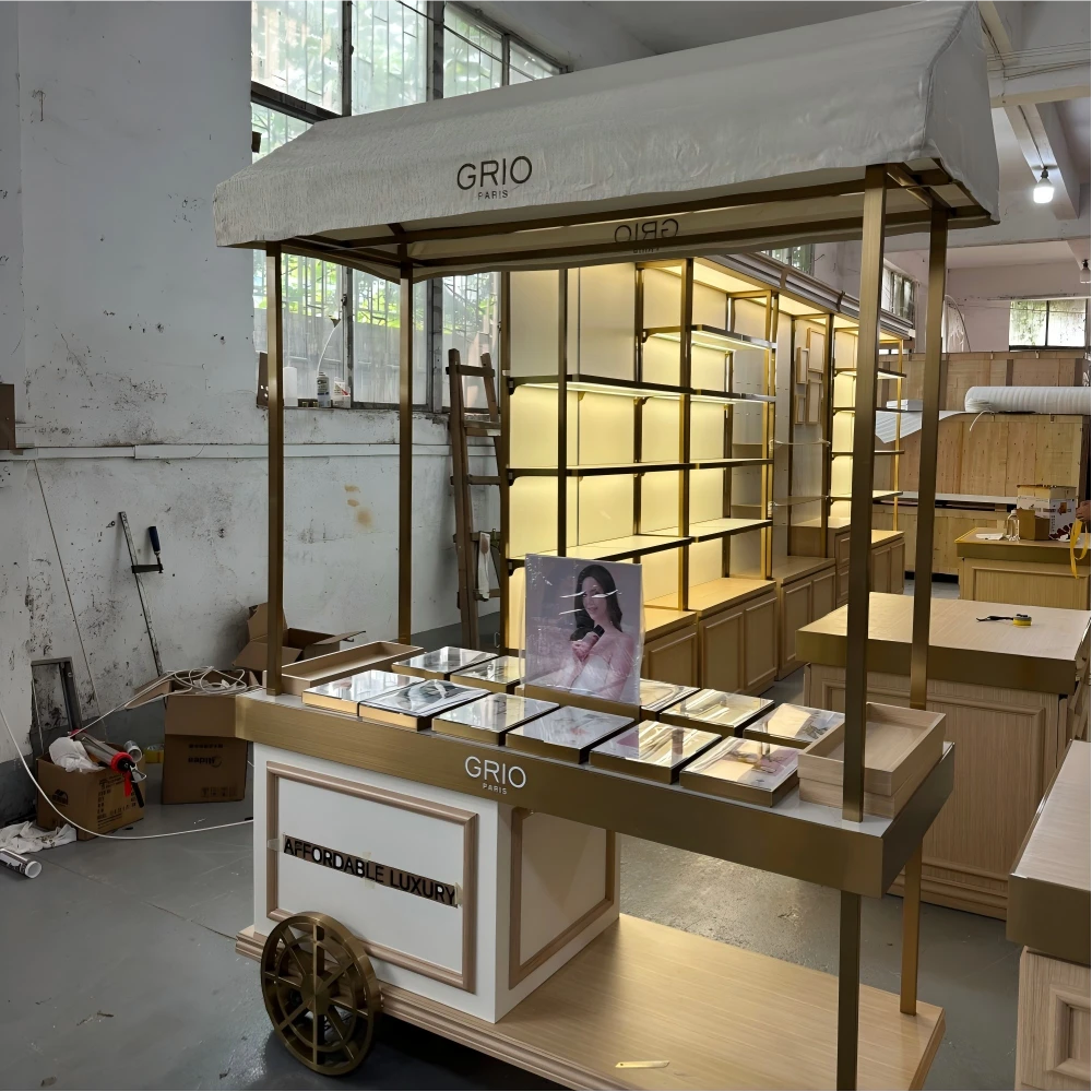 Tall illuminated display cabinet with brushed gold frame, LED coves and glass shelving in a retail design and build production sample
