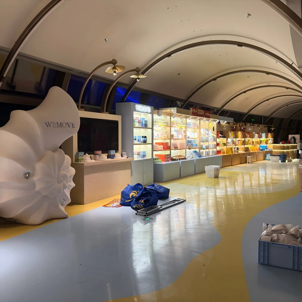 Retail shop interior design featuring a large branded sculpture and continuous display cabinetry in an airport concourse installation