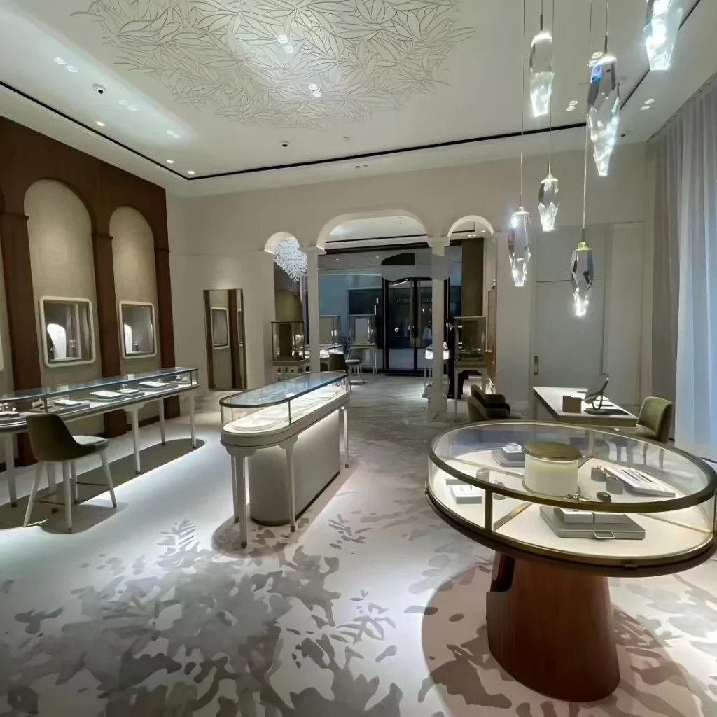 Circular pedestal case and oval gondola counter beneath a botanical relief ceiling in a classical jewelry salon