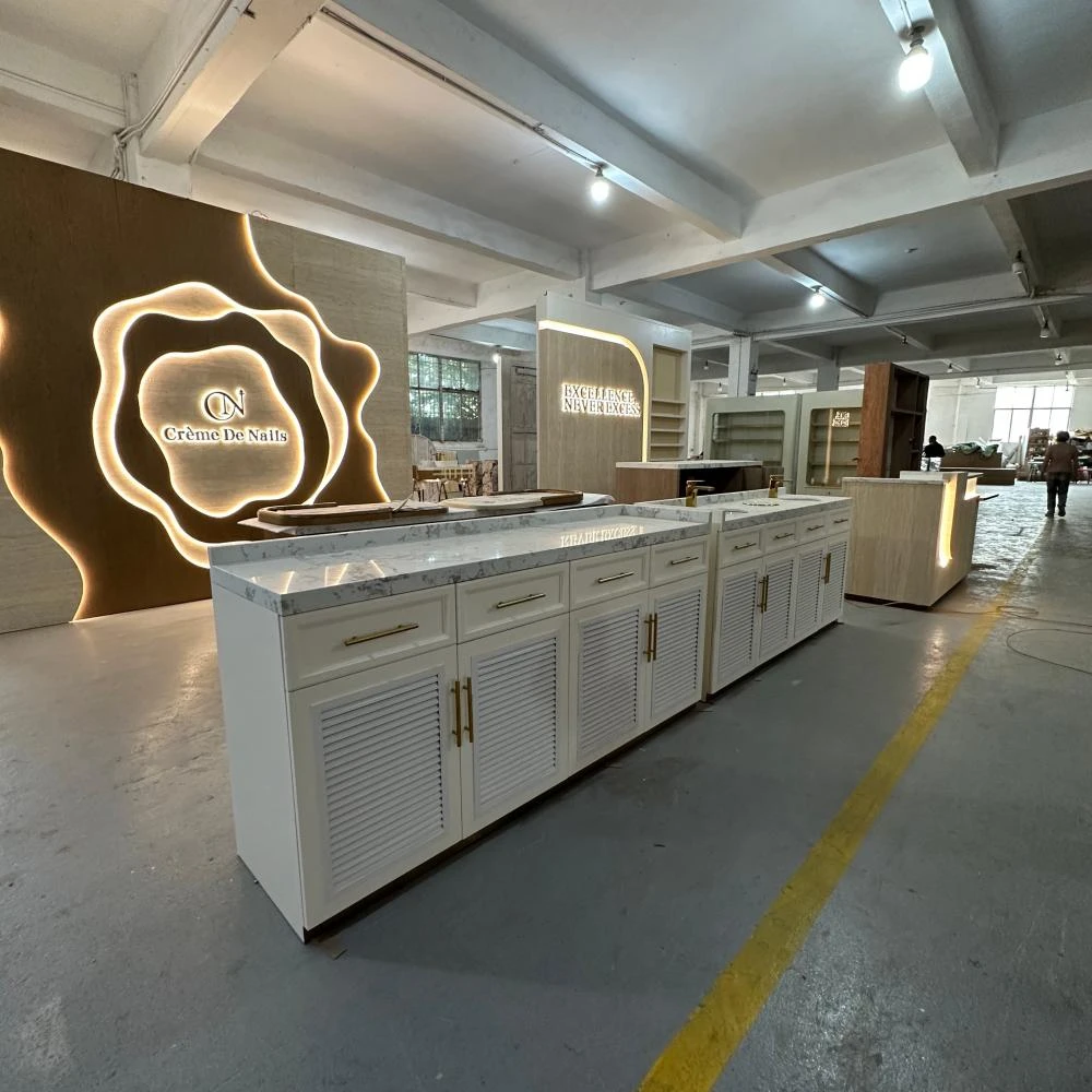 Cream storage wall with marble service island and CNC-carved logo panel in this nail salon interior design factory sample