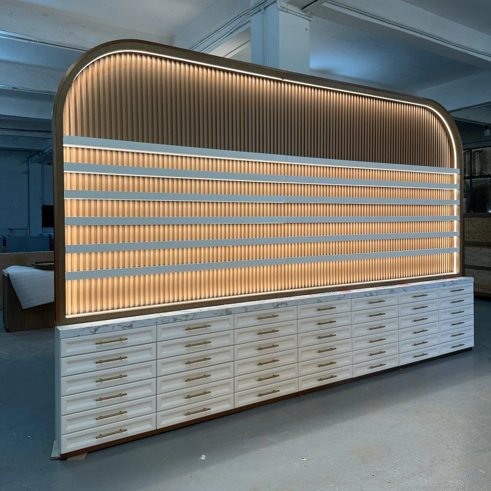 Double-sided fluted shutter wall with brass pull handles, concealed warm LED channels and arched silhouette in this nail salon cabinet factory sample