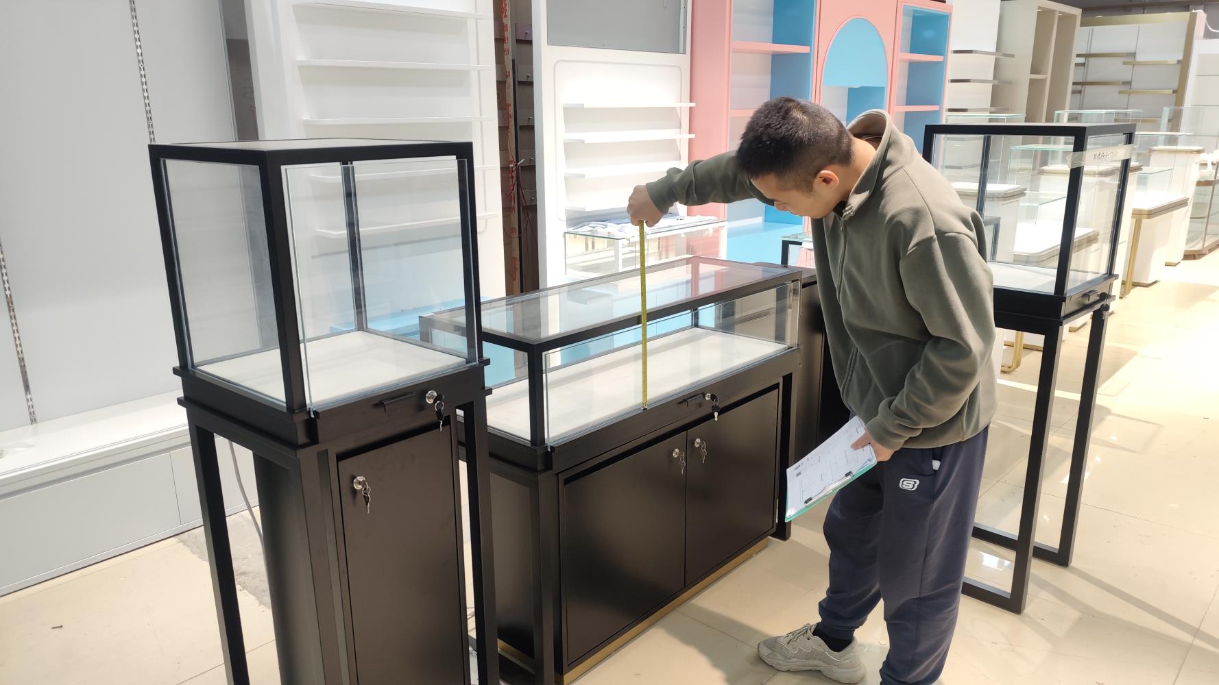 QC inspector measuring a glass display case against the drawing