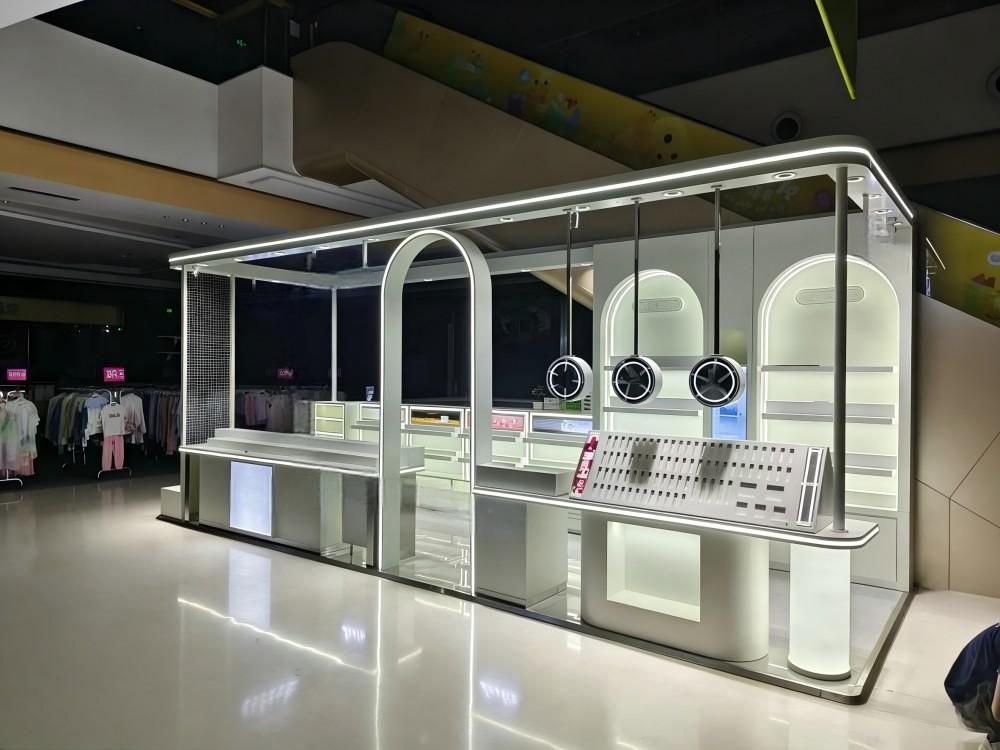 Finished silver-white makeup mall kiosk with LED fascia lighting operating on a busy shopping mall floor