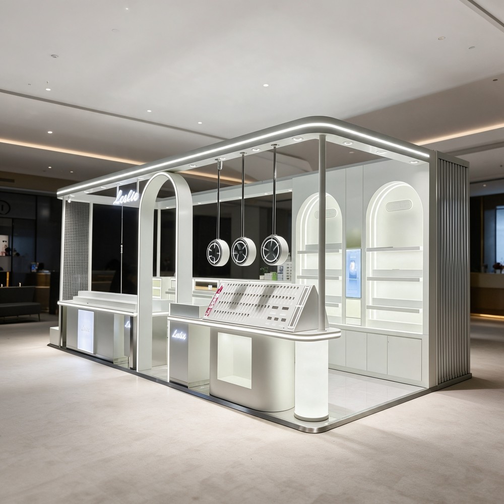 silver-white futuristic makeup kiosk for mall on pure white background with lighted fascia, arched niches, hanging ring lights and lipstick tester bar