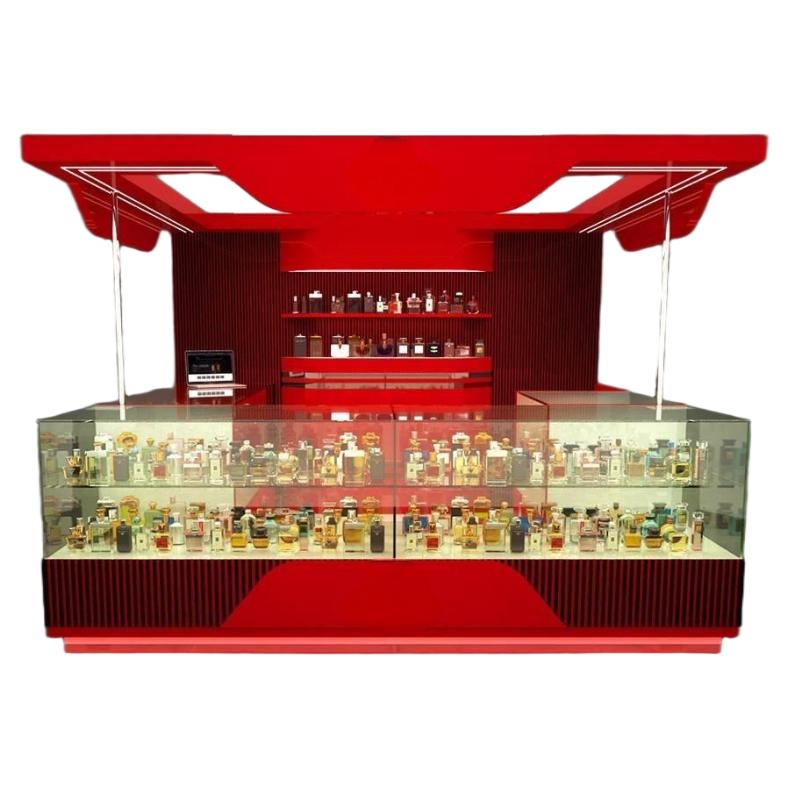 bold red perfume kiosk design with winged lit canopy, fluted back wall stocked with bottles and twin glass display counters